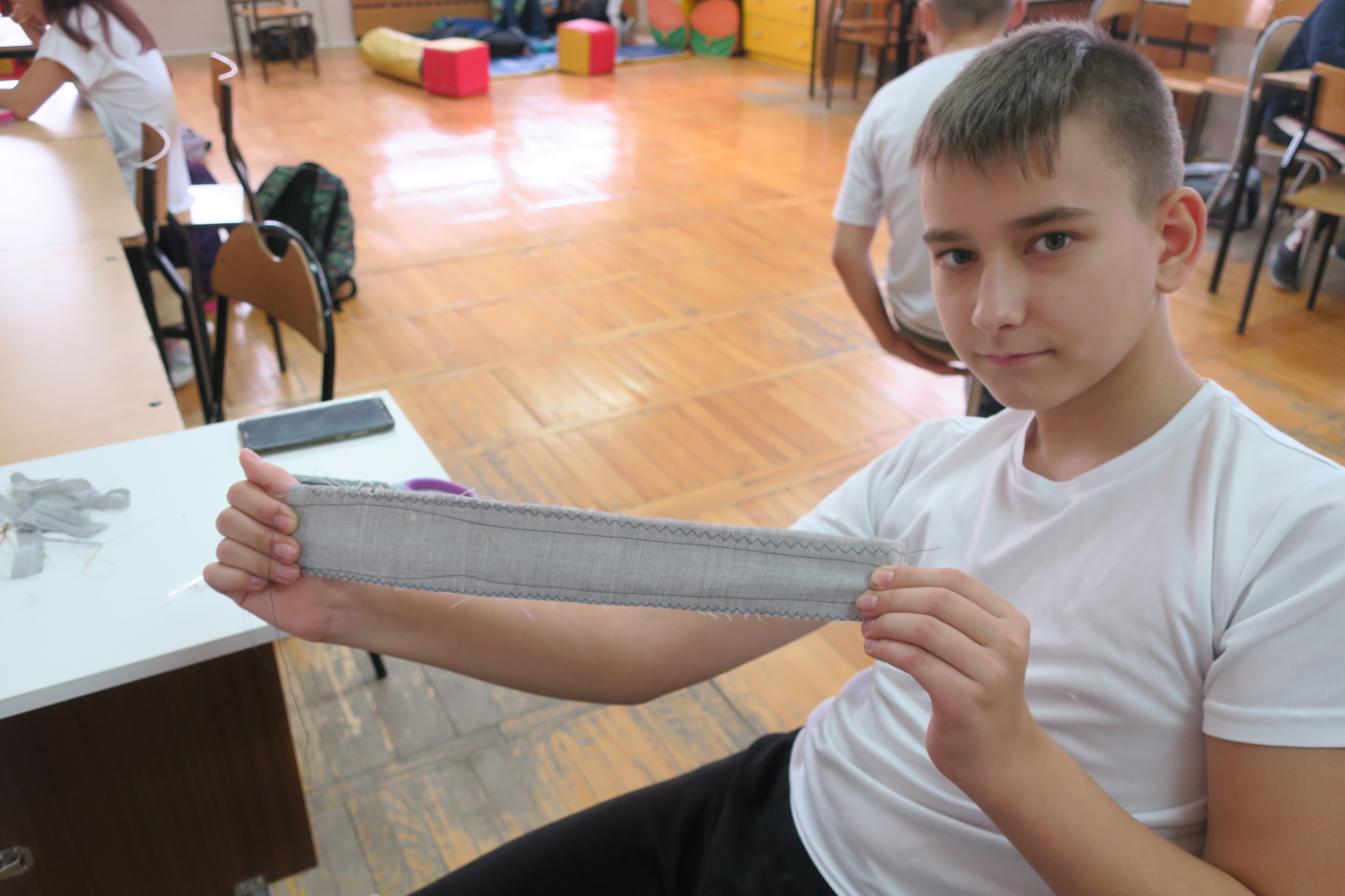 Uczeń pokazujący ściegi na tkaninie