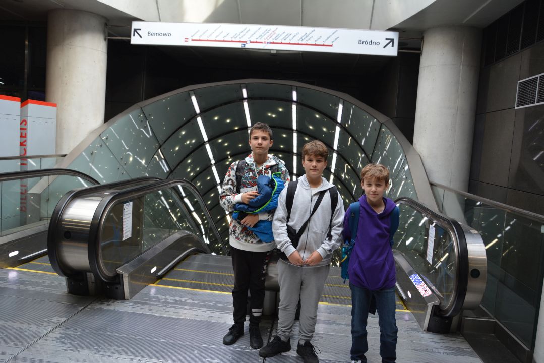 Trzej chłopcy przed zejściem do Warszawskiego metra na stacji Centrum Nauki Kopernik
