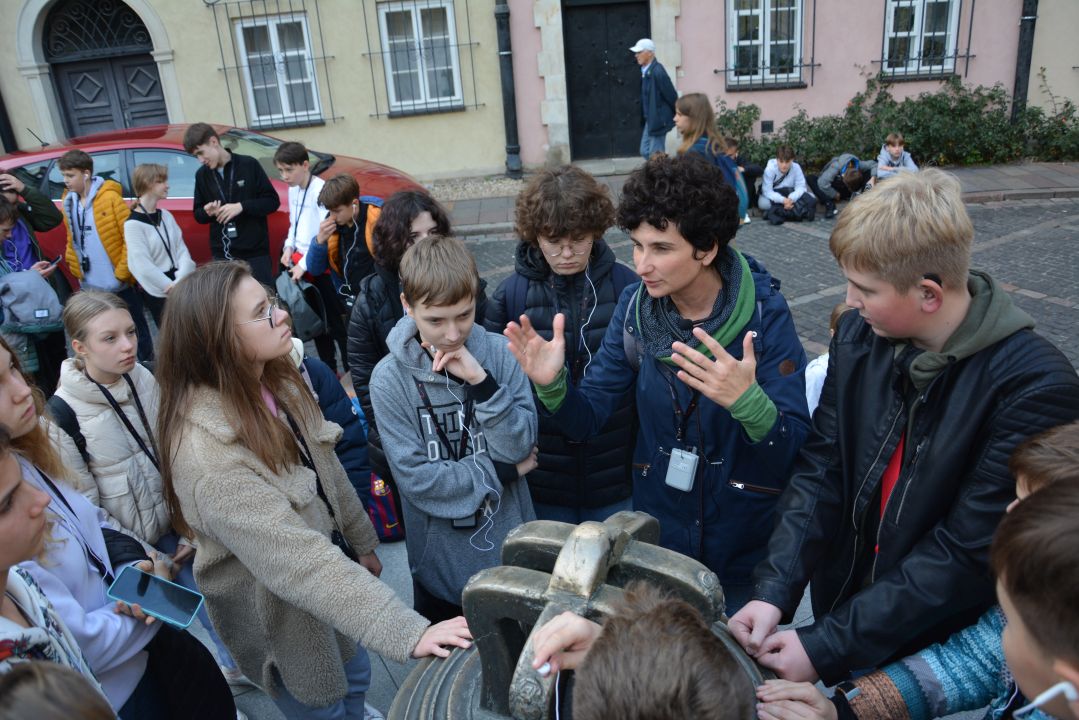 Grupa uczniów wraz z przewodnikiem przy Dzwonie na Kanonii w Warszawie