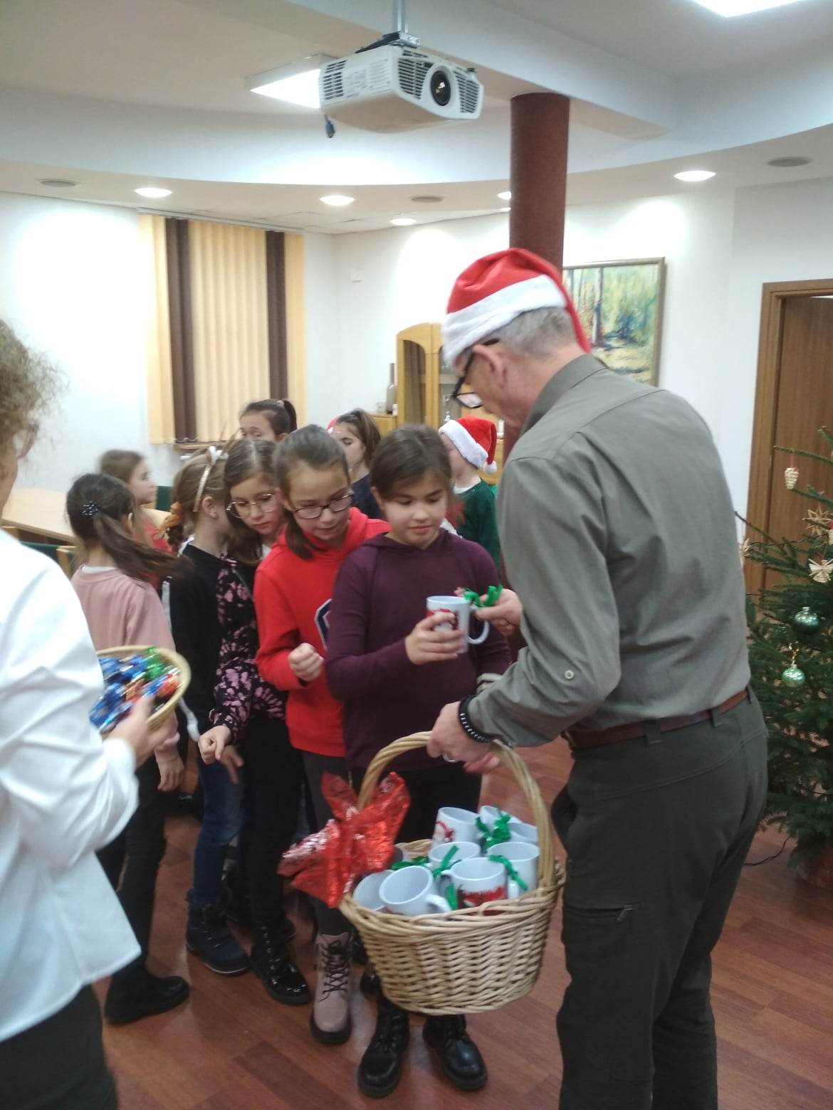 Dzieci odbierają piękne kubeczki z Mikołajem