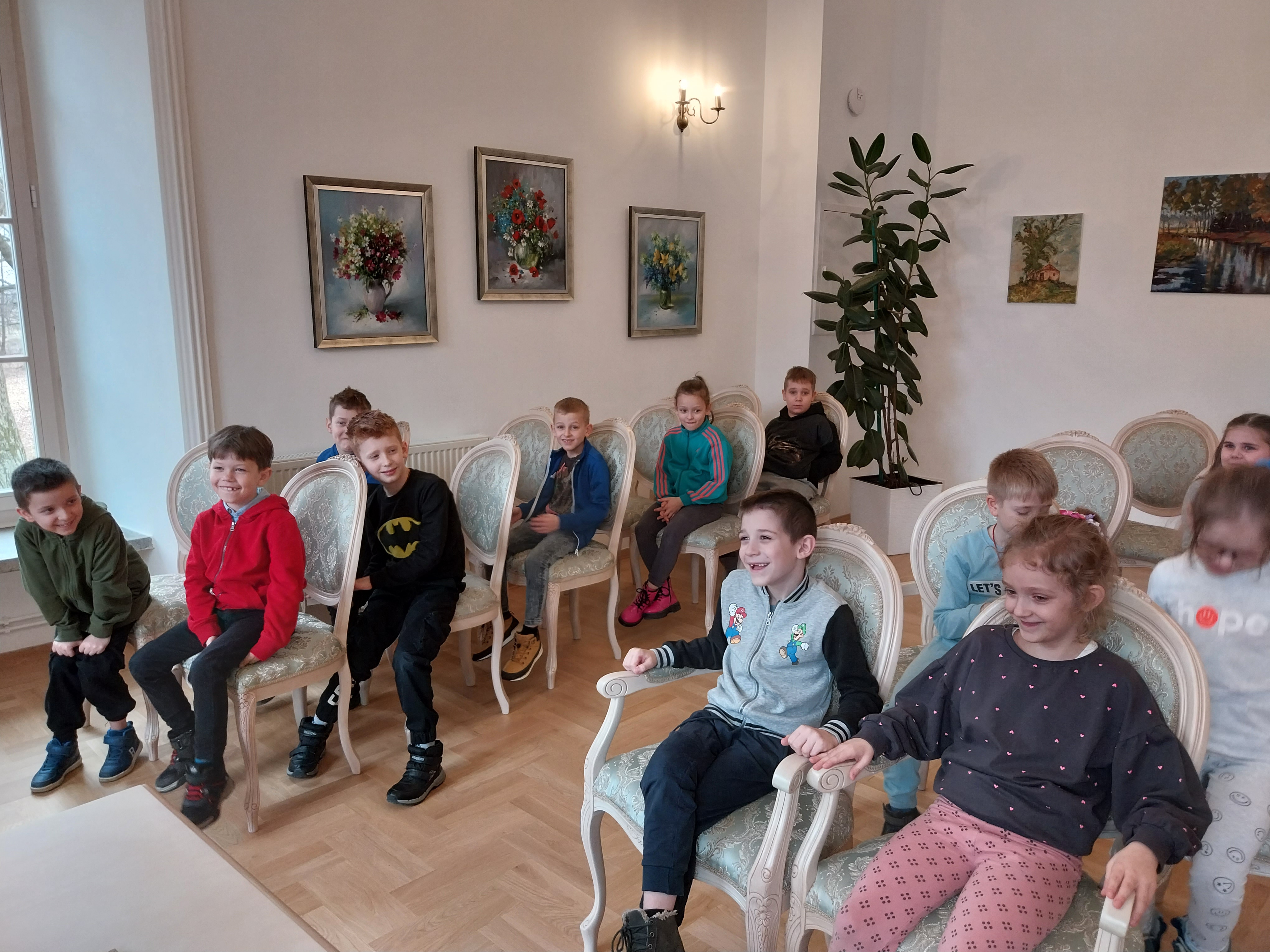 Grupa dzieci siedzi w sali balowej