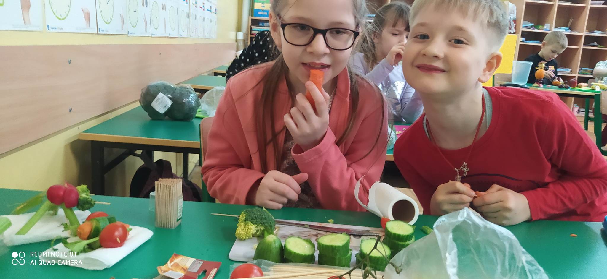 Uśmiechnięty chłopiec i dziewczynka wykonują pracę  z warzyw