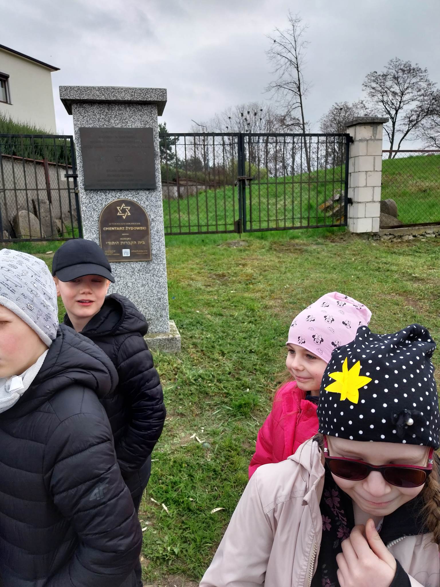 Uczniowie klasy pierwszej przed bramą cmentarza żydowskiego w Staszowie