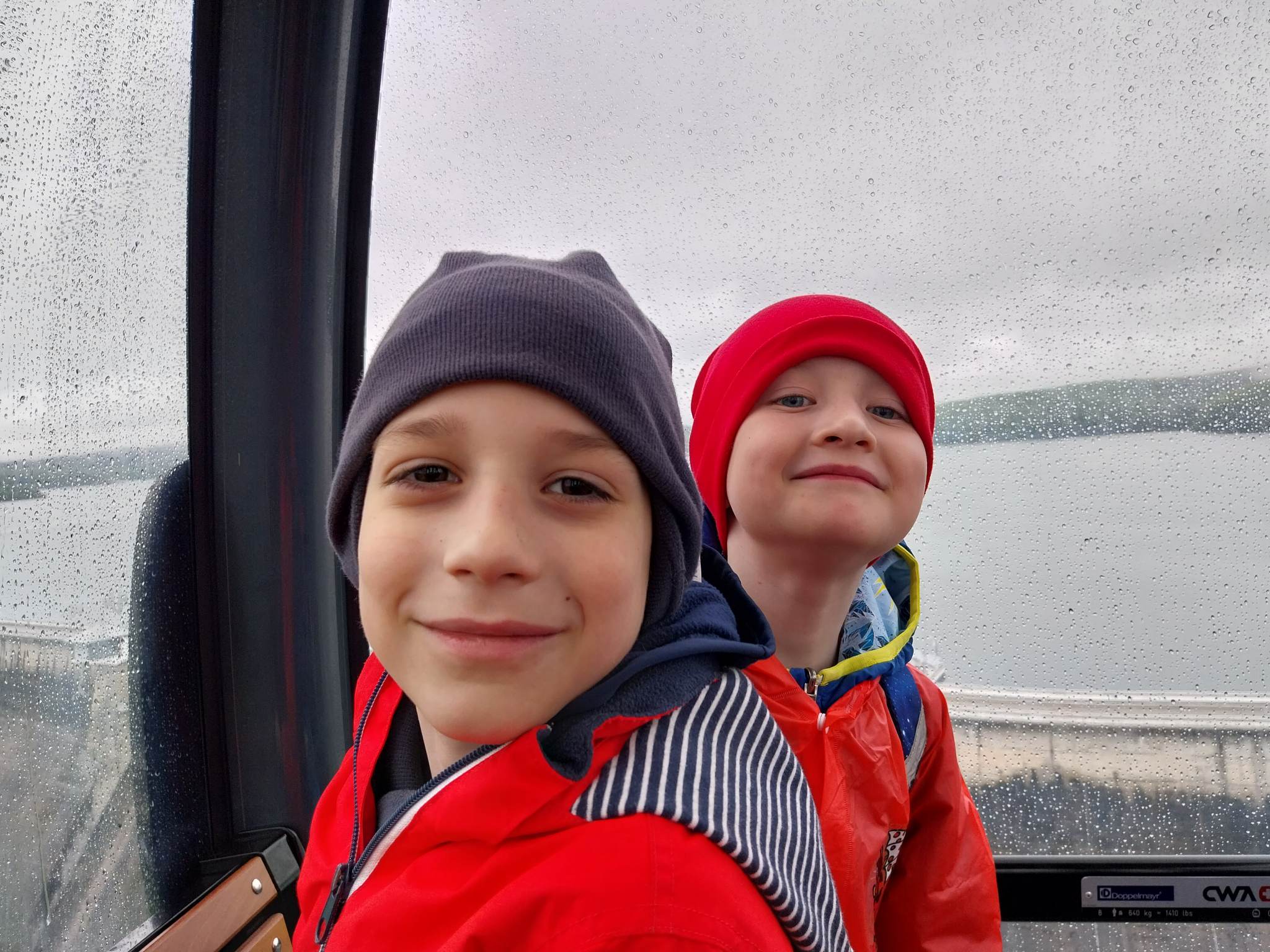Dwaj uśmiechnięci chłopcy w wagoniku kolejki gondolowej