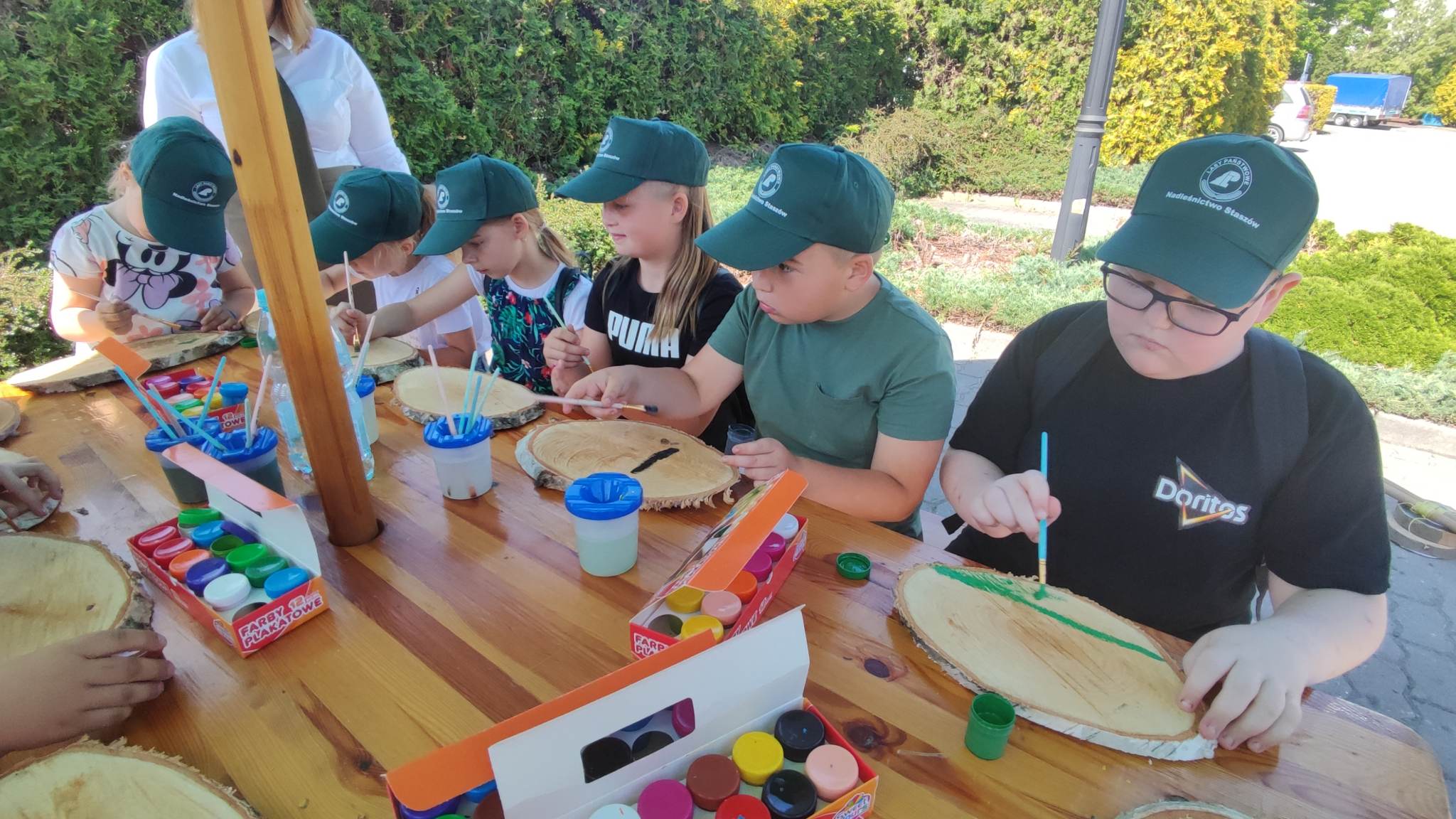 Dzieci malują obrazki na drewnianych deseczkach