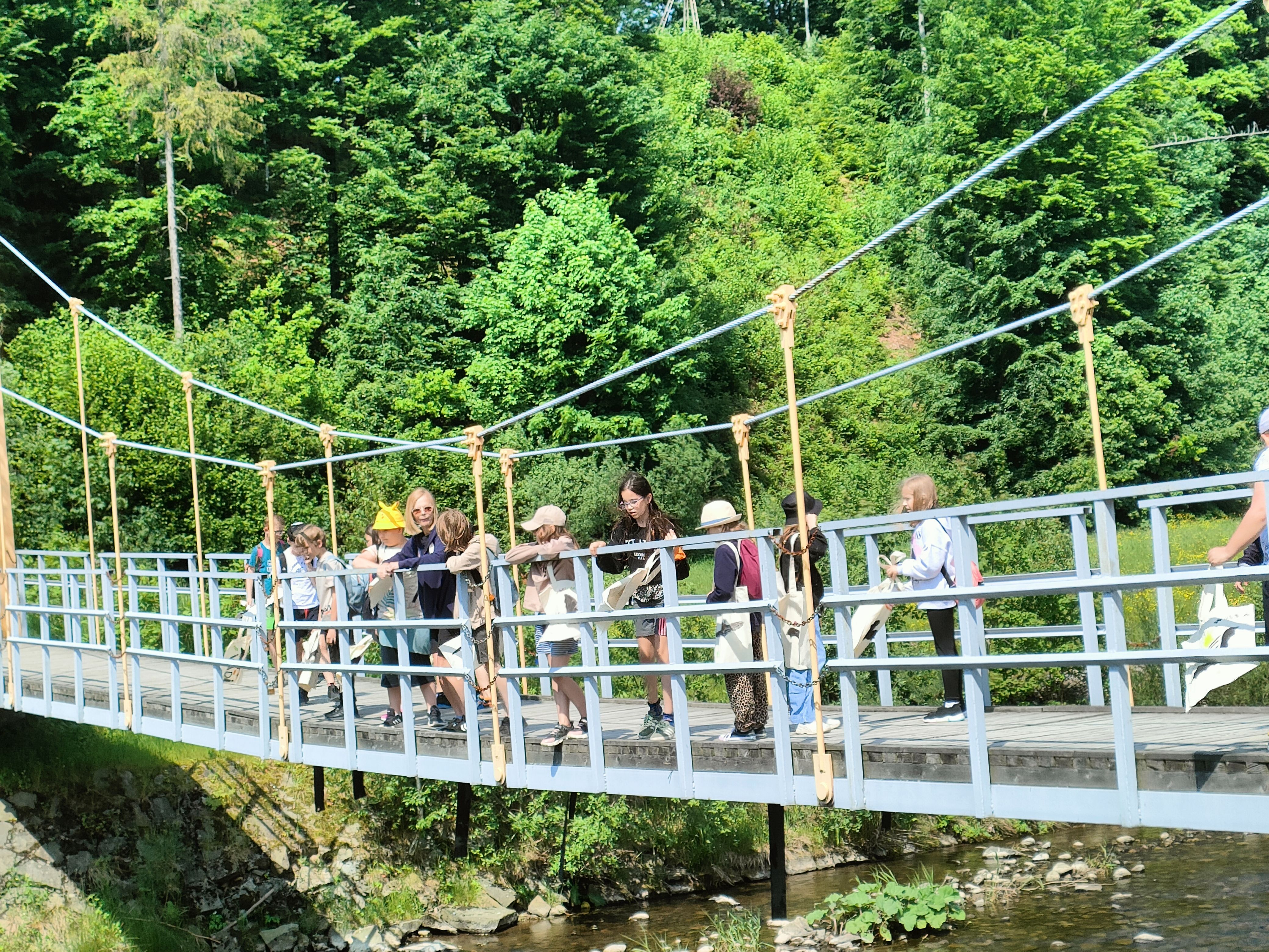 Grupa uczniów wraz z wychowawcą na wiszącym moście na Wiśle