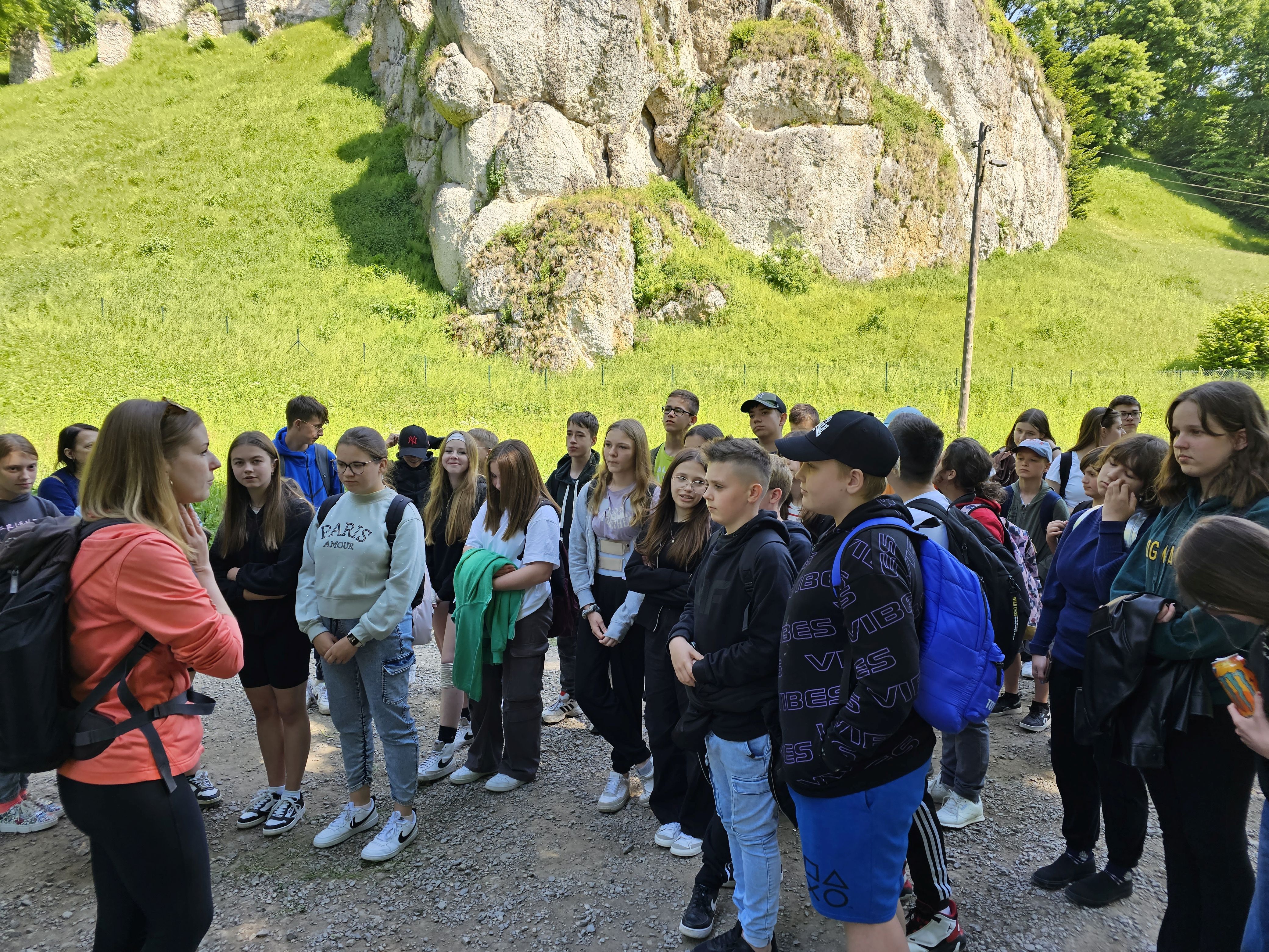 Grupa uczniów słucha przewodnika podczas zwiedzania Ojcowskiego Parku Narodowego