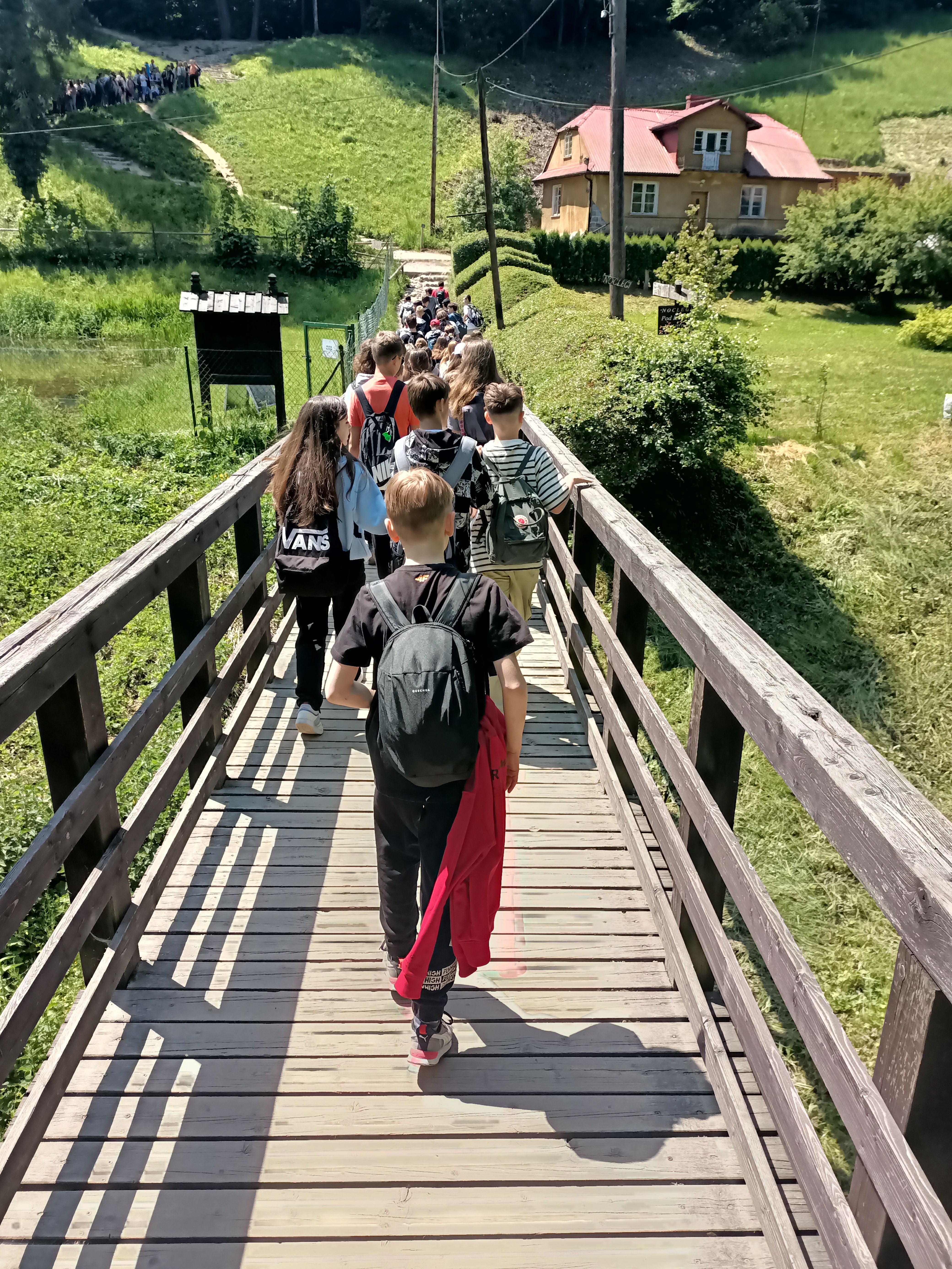 Uczniowie przechodzą przez drewniany mostek