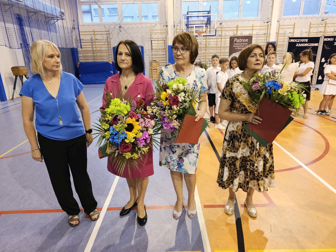 Wicedyrektor, trzy nauczycielki odchodzące na emeryturę z bukietami kwiatów